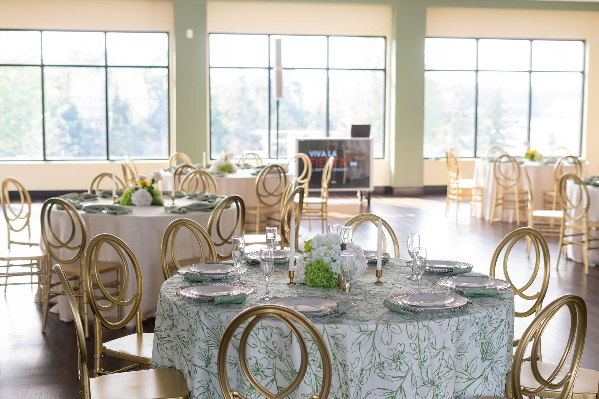 Bright event room with round tables and floor-to-ceiling windows set for a corporate event