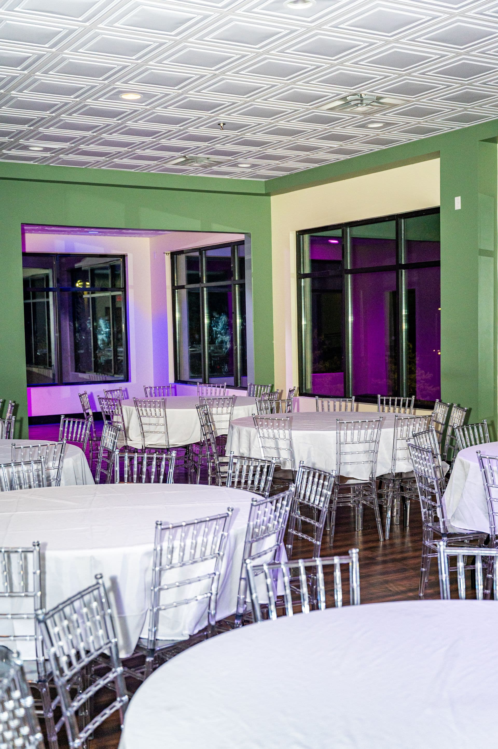 Event room with purple uplighting and white round tables