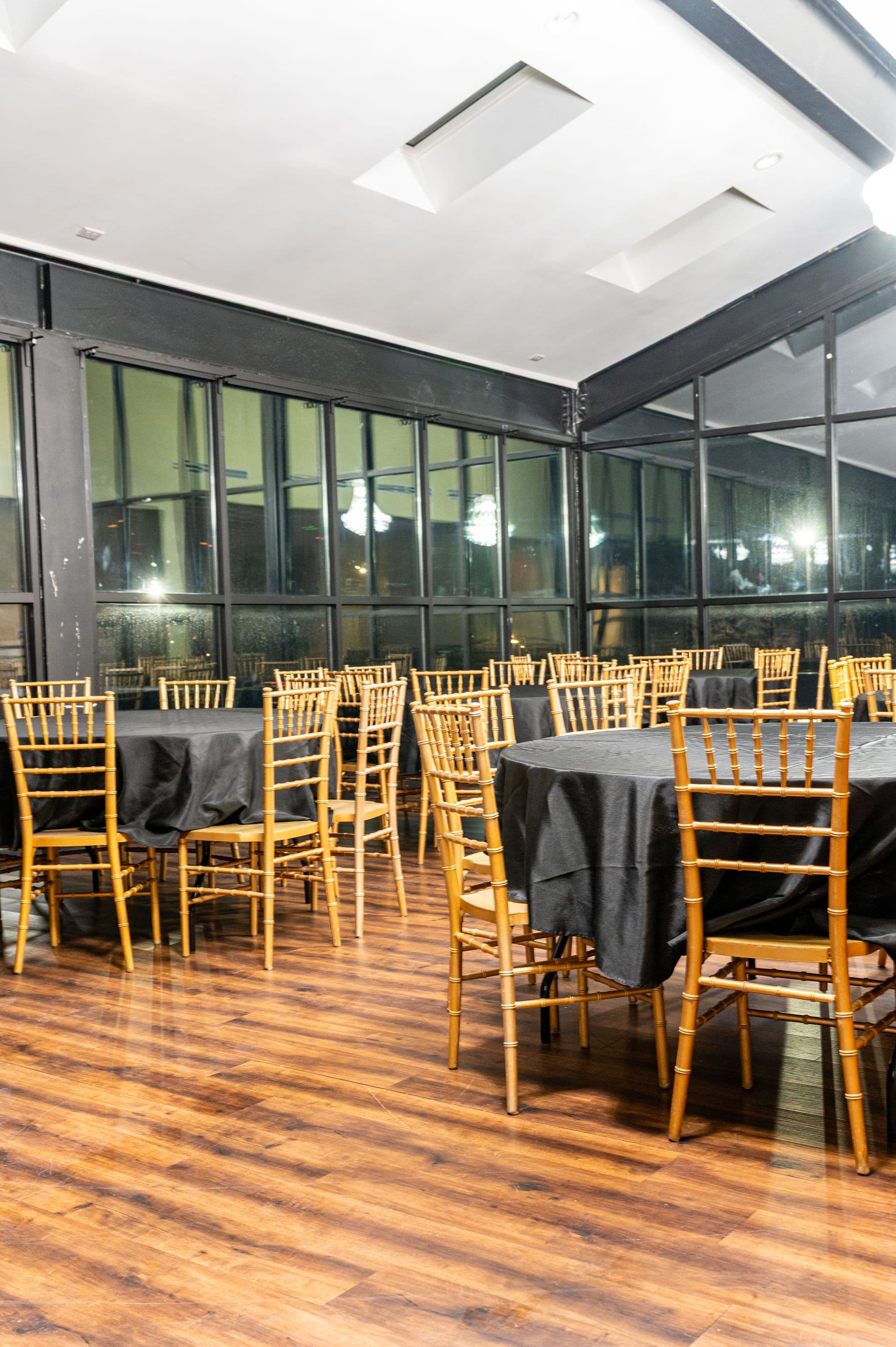 Event room with chandeliers, black linens and gold chiavari chairs at BB's Events