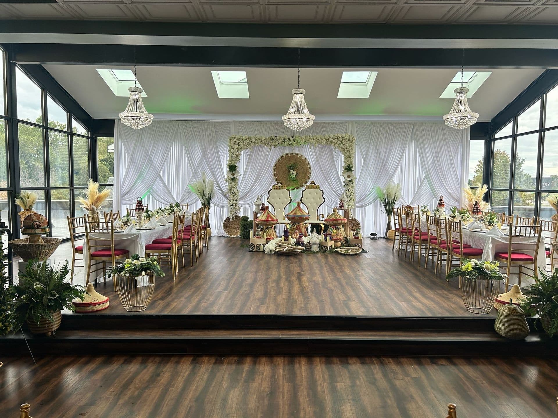 Cultural wedding setup with draped stage, chandeliers and banquet tables at BB's Events & Restaurant